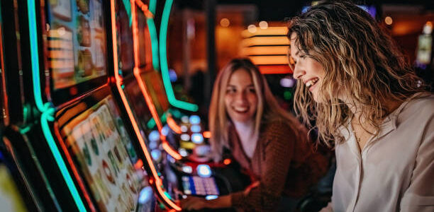 Girl friends gambling in casino on slot machinery
